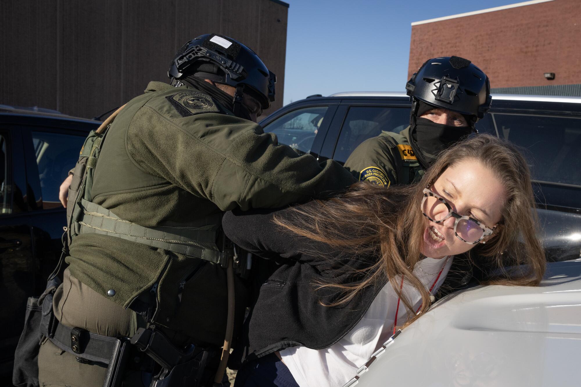 A woman is taken into custody by Border Patrol agents