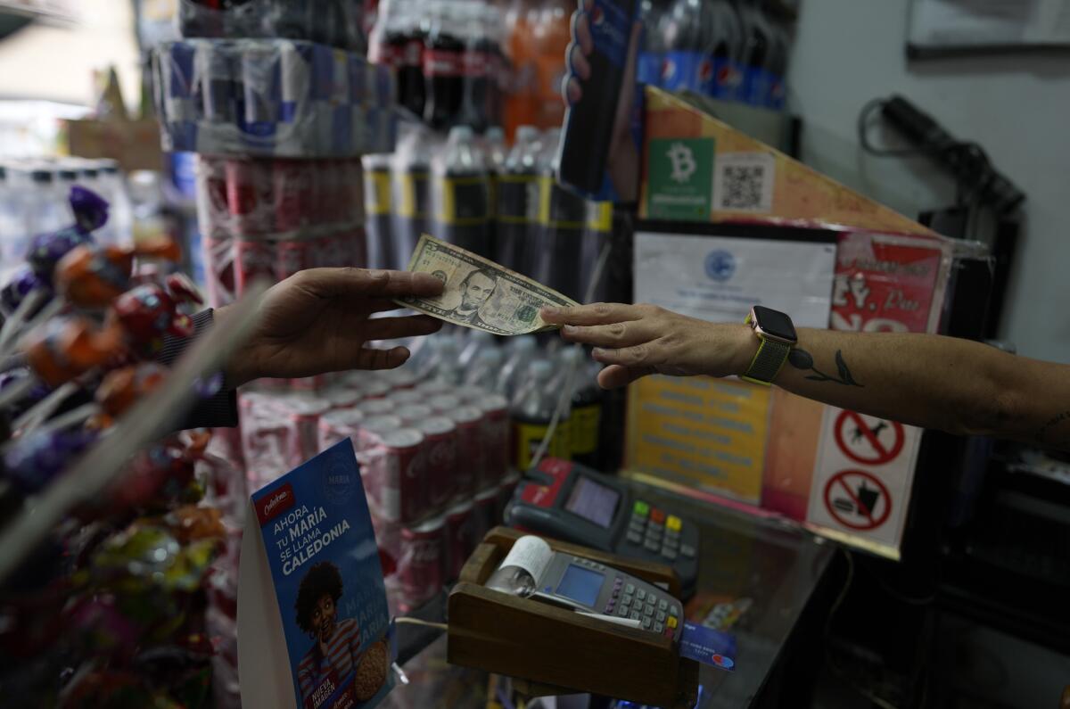 Rim Hassam entrega cambio en moneda estadounidense a un cliente en Caracas, Venezuela, 
