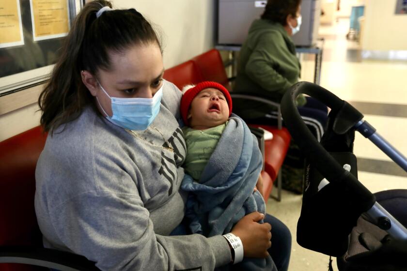 A woman sits with her son , in the emergency room of a hospital.