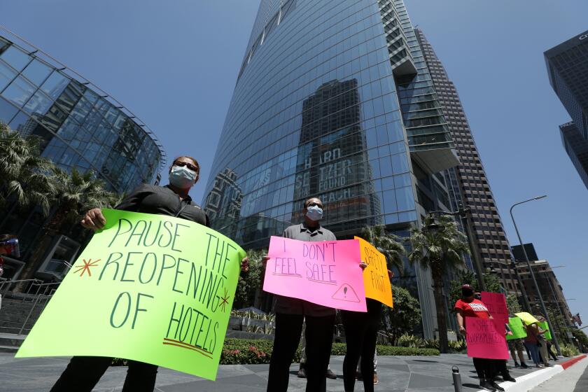 LOS ANGELES, CA - JULY 08: Hotel workers protest for their safety in front of the InterContinental Los Angeles Downtown on Wednesday, July 8, 2020 in Los Angeles, CA. A spokesperson said a survey of hospitality workers found that the lack of safety measures such as having hand sanitizer, gloves and companies' lack of enforcing social distancing rules, were risking the workers' health. The spokesperson added that given the choice between saving the economy or saving their families, they'll save their families. (Myung J. Chun / Los Angeles Times)