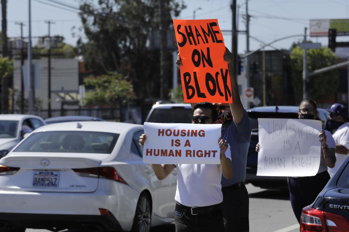 People hold anti-eviction signs as cars pass by