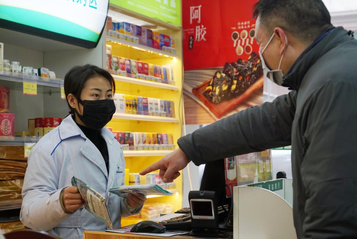 A worker sells masks at a pharmacy in Wuhan in January.