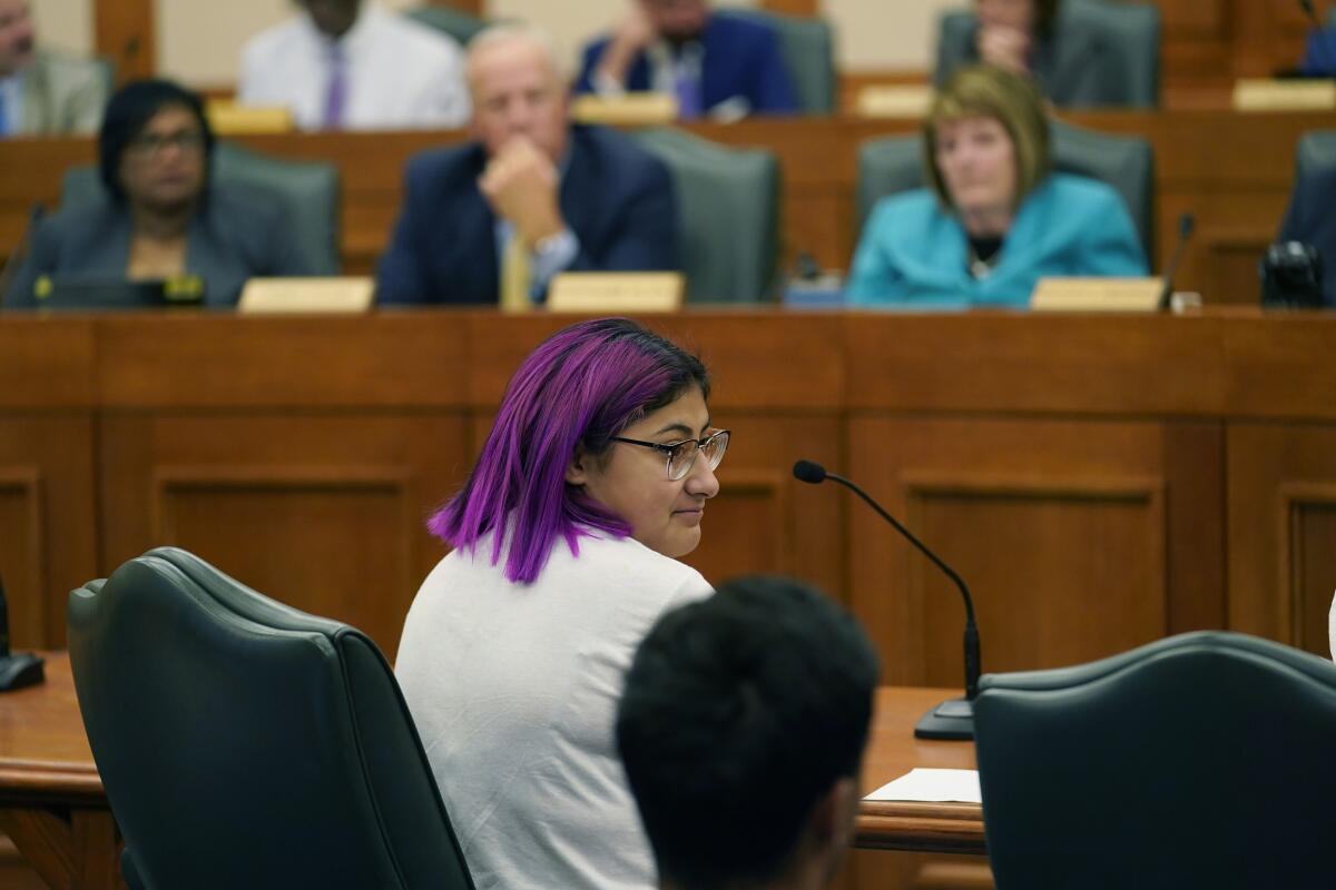 A girl with purple hair at a courtroom bench 