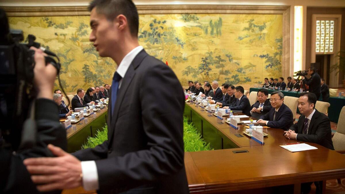 A security official escorts journalists from the opening session of trade negotiations between U.S. and Chinese trade representatives Feb. 14 at the Diaoyutai State Guesthouse in Beijing.