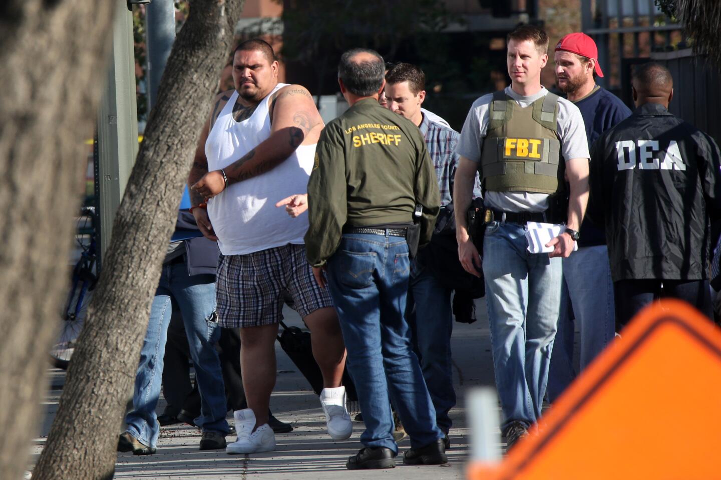 A suspect is processed in downtown Los Angeles on Wednesday as authorities round up members of the Big Hazard gang indicted under federal RICO statutes.