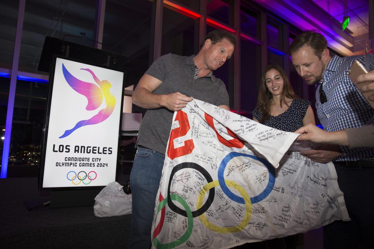 Athletes and supporters hold up a flag bearing signatures of past and present olympians during the logo unveiling for the Los Angeles Olympic Games 2024 bid on Feb. 16.