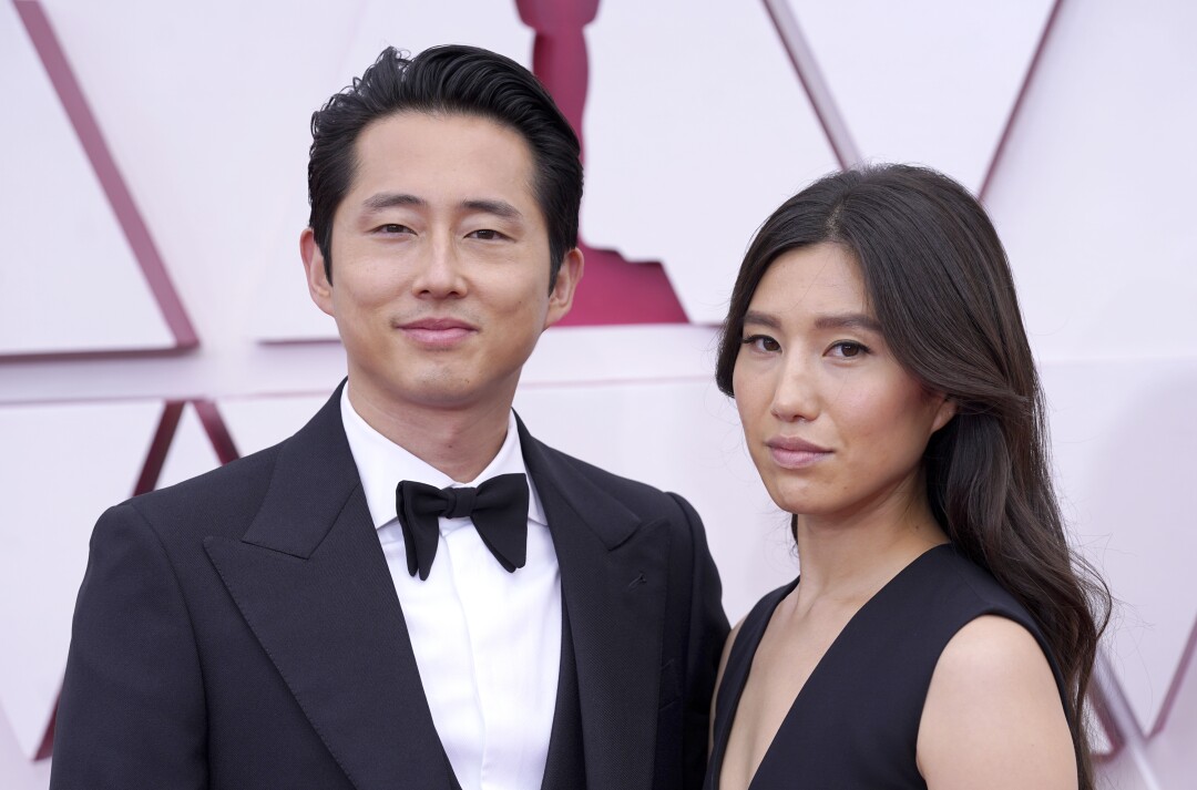 Steven Yeun in a tuxedo and Joana Pak in a dark dress