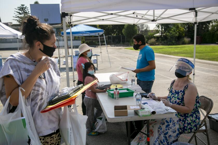 LOS ANGELES, CA - AUGUST 14: School Coordinator Lali Oustinovskaya, right, talks with parent Byata Dikker, left, before she leaves a technology and supply pickup event before the start of the school year at Gardner Elementary School on Friday, Aug. 14, 2020 in Los Angeles, CA. (Josie Norris / Los Angeles Times)