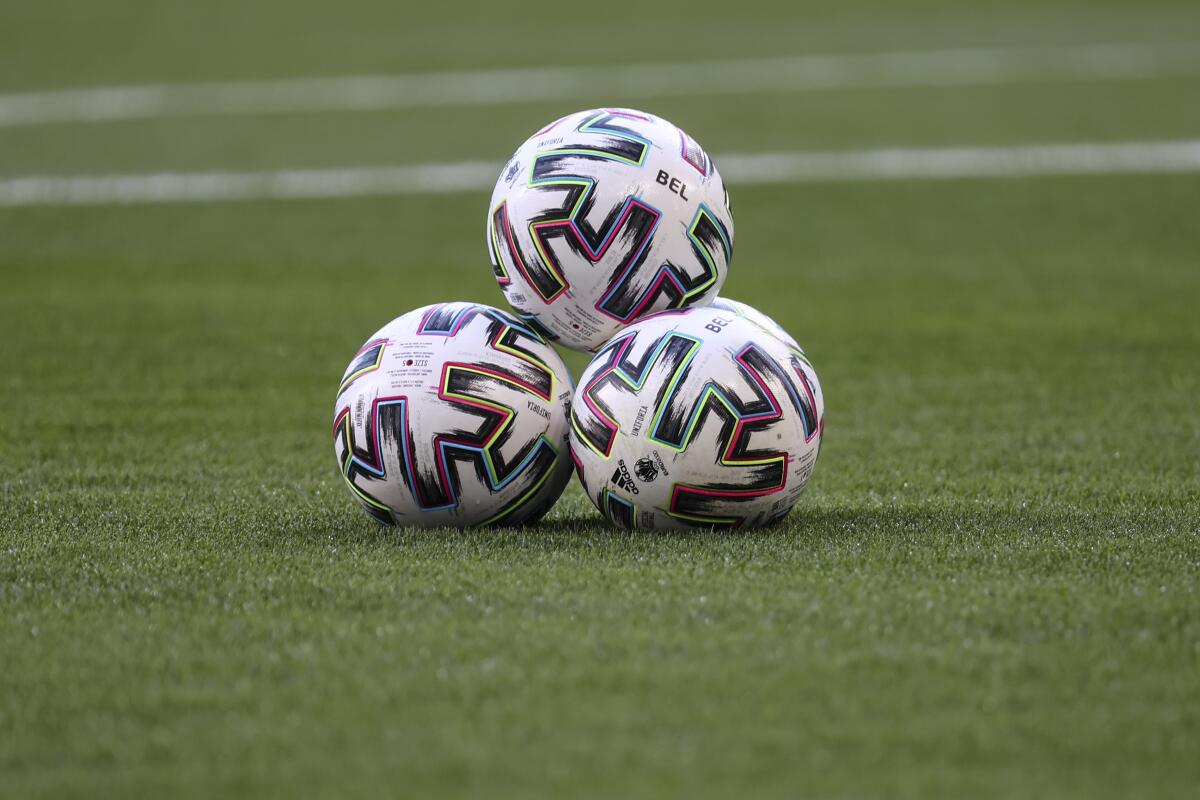 Soccer balls stacked on the pitch.