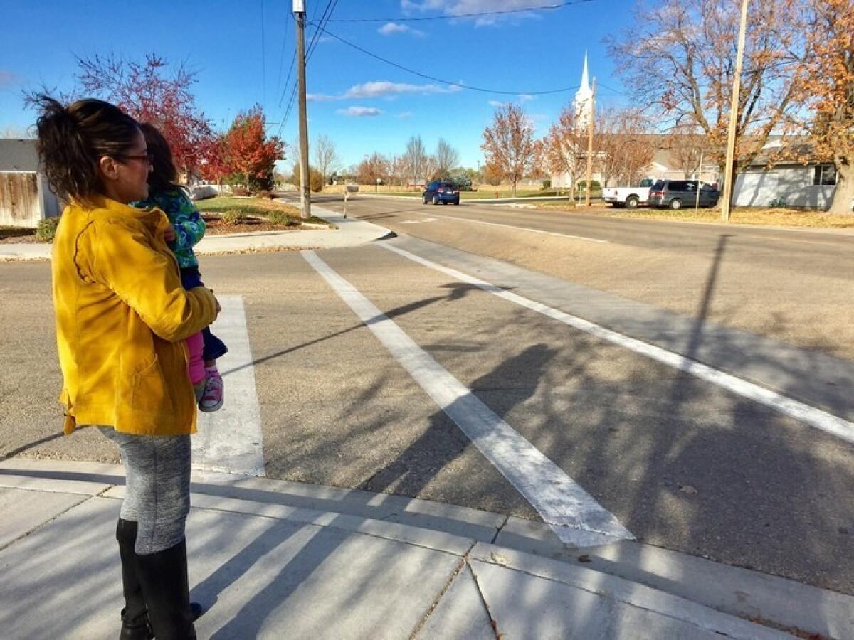 Janeth Calderon, holding daughter Sarnay, 2, waits for her children's school bus in Caldwell, Idaho.