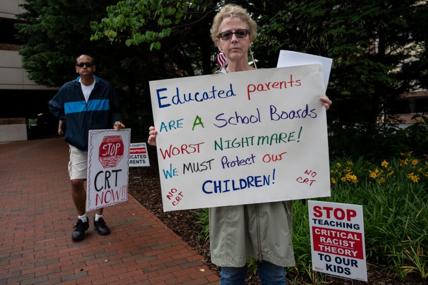 People hold up signs during a rally against "critical race theory" (CRT) being taught in schools at the Loudoun County Government center in Leesburg, Virginia on June 12, 2021. - "Are you ready to take back our schools?" Republican activist Patti Menders shouted at a rally opposing anti-racism teaching that critics like her say trains white children to see themselves as "oppressors." "Yes!", answered in unison the hundreds of demonstrators gathered this weekend near Washington to fight against "critical race theory," the latest battleground of America's ongoing culture wars. The term "critical race theory" defines a strand of thought that appeared in American law schools in the late 1970s and which looks at racism as a system, enabled by laws and institutions, rather than at the level of individual prejudices. But critics use it as a catch-all phrase that attacks teachers' efforts to confront dark episodes in American history, including slavery and segregation, as well as to tackle racist stereotypes. (Photo by ANDREW CABALLERO-REYNOLDS / AFP) (Photo by ANDREW CABALLERO-REYNOLDS/AFP via Getty Images)