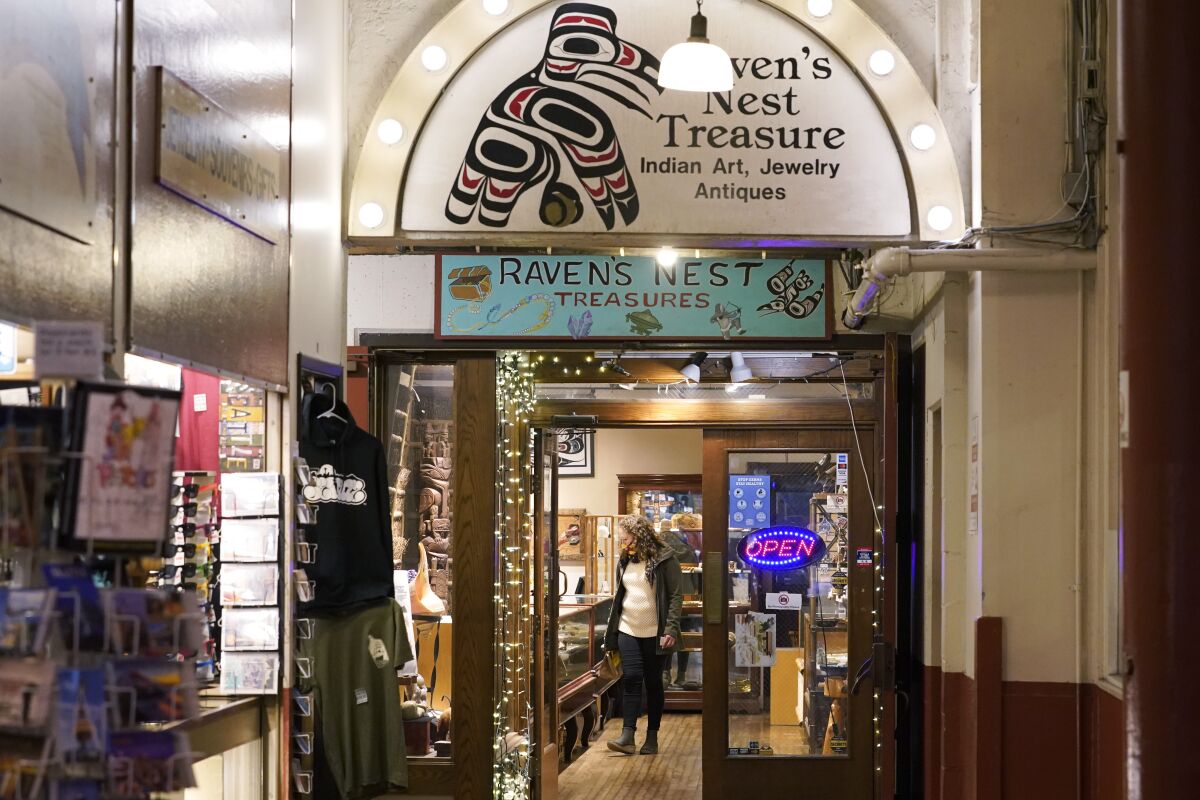 A person browses offerings in the Raven's Nest Treasure shop in Pike Place Market, Friday, Dec. 10, 2021, in Seattle. Two artists are facing federal charges that they faked Native American heritage to sell works the shop and another gallery in downtown Seattle. The men were charged separately with violating the Indian Arts and Crafts Act, which prohibits misrepresentation in marketing American Indian or Alaska Native arts and crafts. (AP Photo/Ted S. Warren)