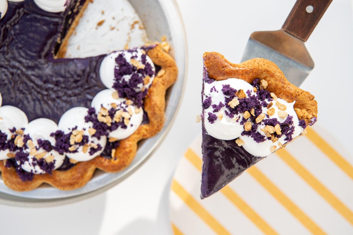 A spatula holds a slice of ube blondie pie next to the rest of the whole pie