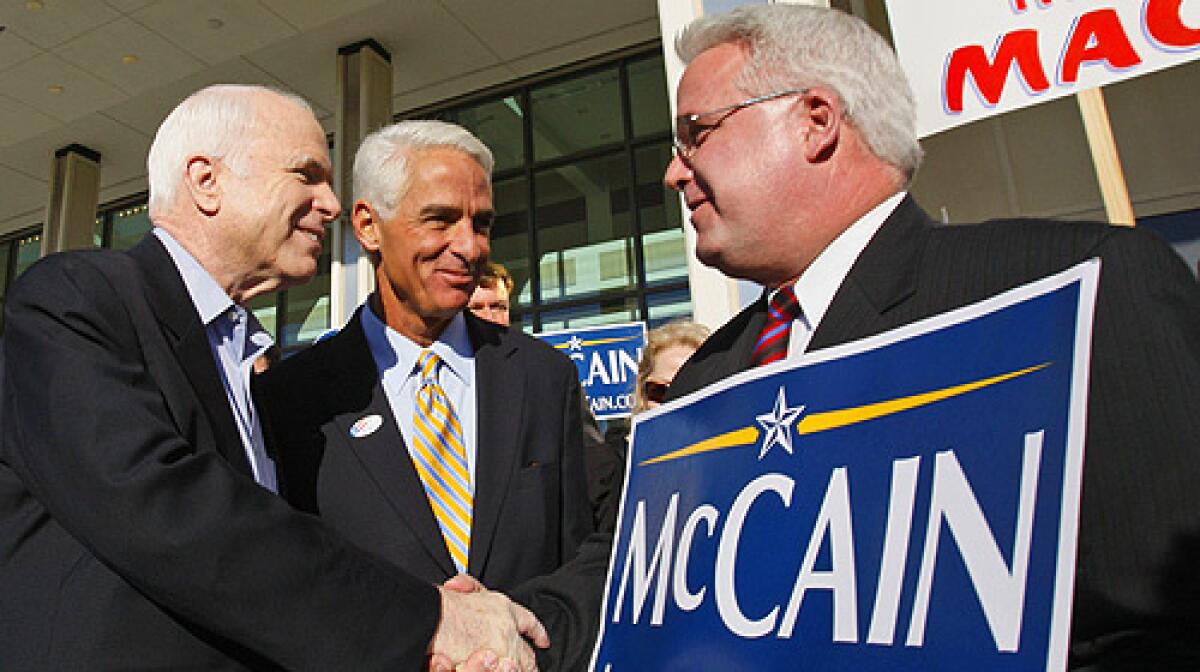 Republican presidential hopeful, Sen. John McCain, R-Ariz., left, accompanied by Florida Gov. Charlie Crist, center, greets a supporter during a visit to a polling station in St. Petersburg, Fla.