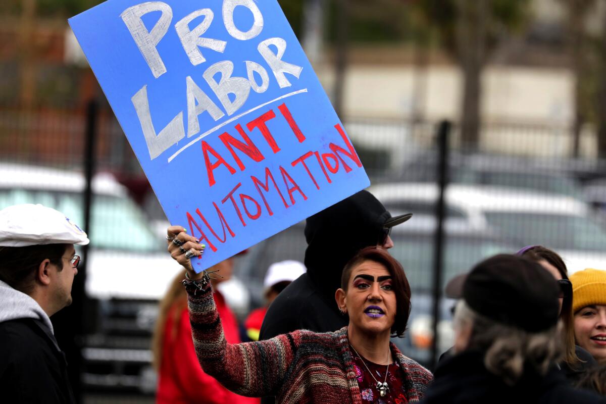 A woman holds a sign reading “Pro Labor. Anti Automation.”