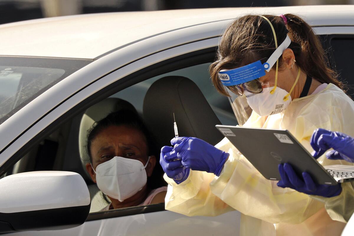 A driver awaits a COVID-19 vaccination in the parking lot of the Forum in Inglewood.