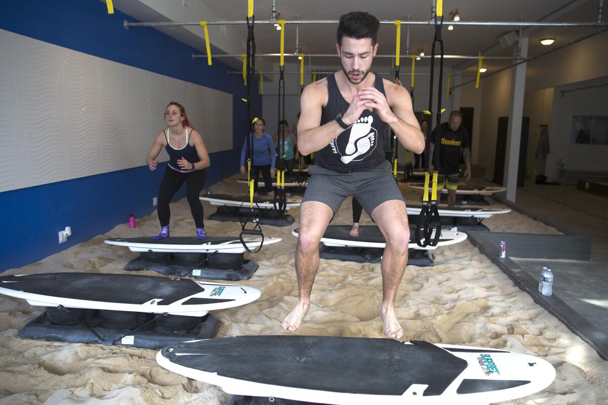 Quinn Crumbley jumps out of the sand onto a surfboard during a class at Sandbox Fitness.
