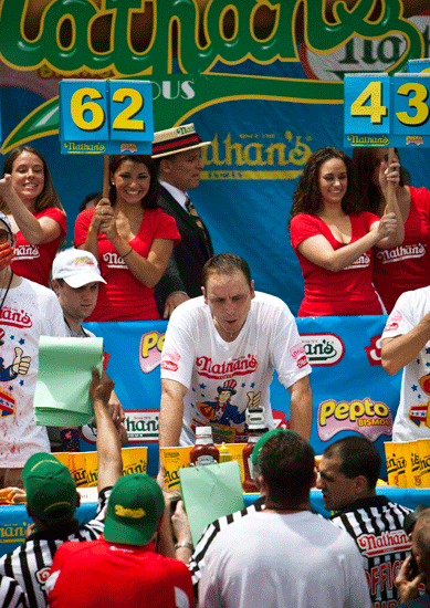 Joey Chestnut (C) rests after eating 62 hot dogs.