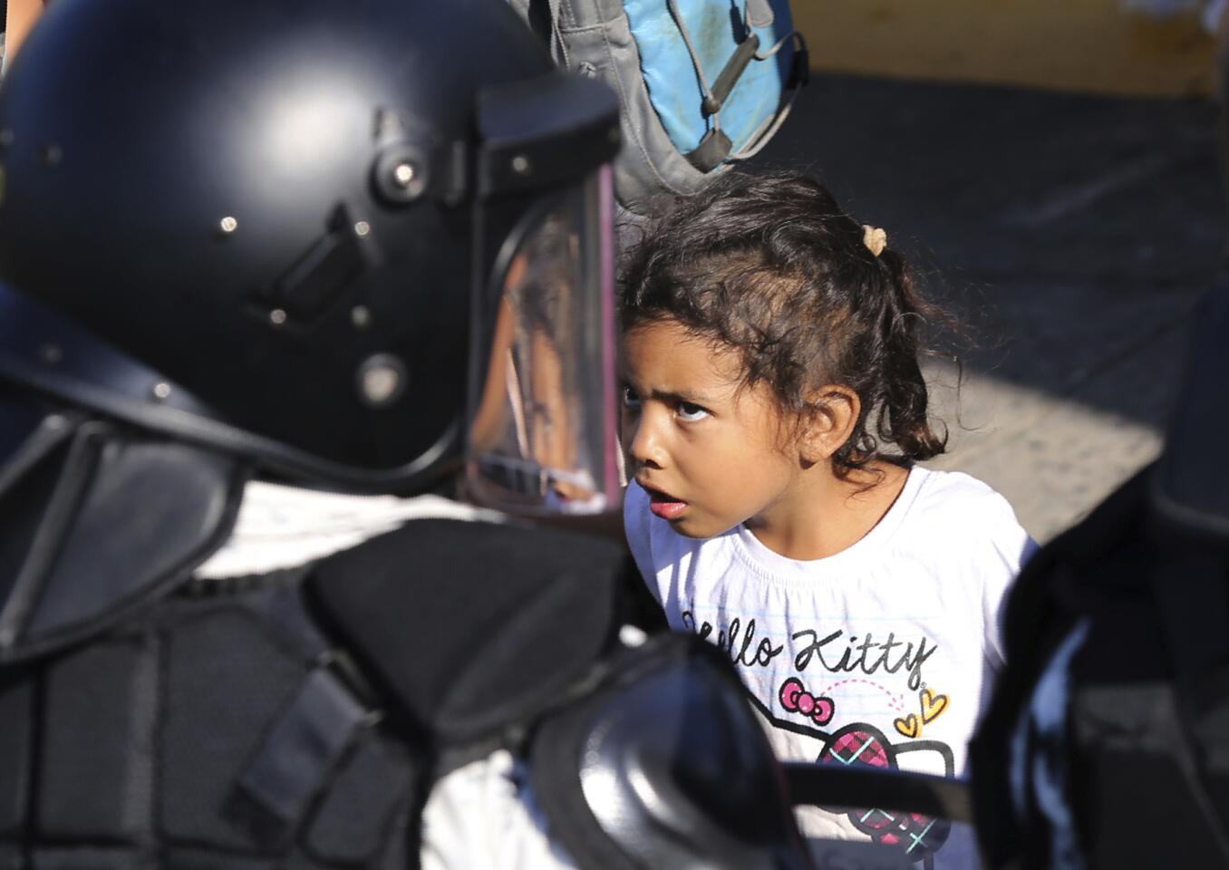 Una niña encara a un efectivo de la guardia nacional mexicana en el cruce fronterizo entre Guatemala y México en Tecún Umán, Guatemala, sábado 18 de enero de 2020. (AP Photo/Marco Ugarte)