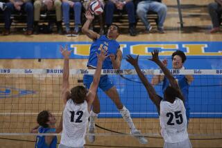 UCLA's Merrick McHenry spikes the ball while jumping above the net during a match against Pepperdine.