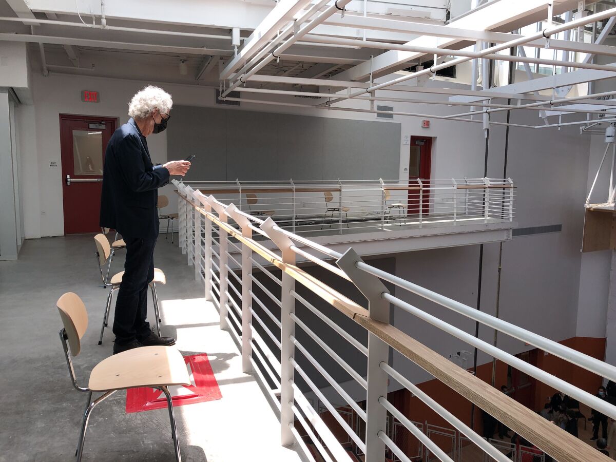 Mark Swed, wearing a face mask, takes pictures from a mezzanine overlooking a performance space