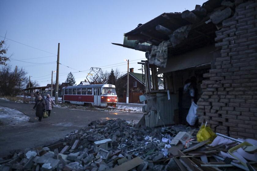 People walk past a damaged part of an house after what Russian officials in Donetsk said it was a shelling by Ukrainian forces, in Donetsk, in Russian-controlled Donetsk region, eastern Ukraine, Tuesday, Jan. 10, 2023. (AP Photo)
