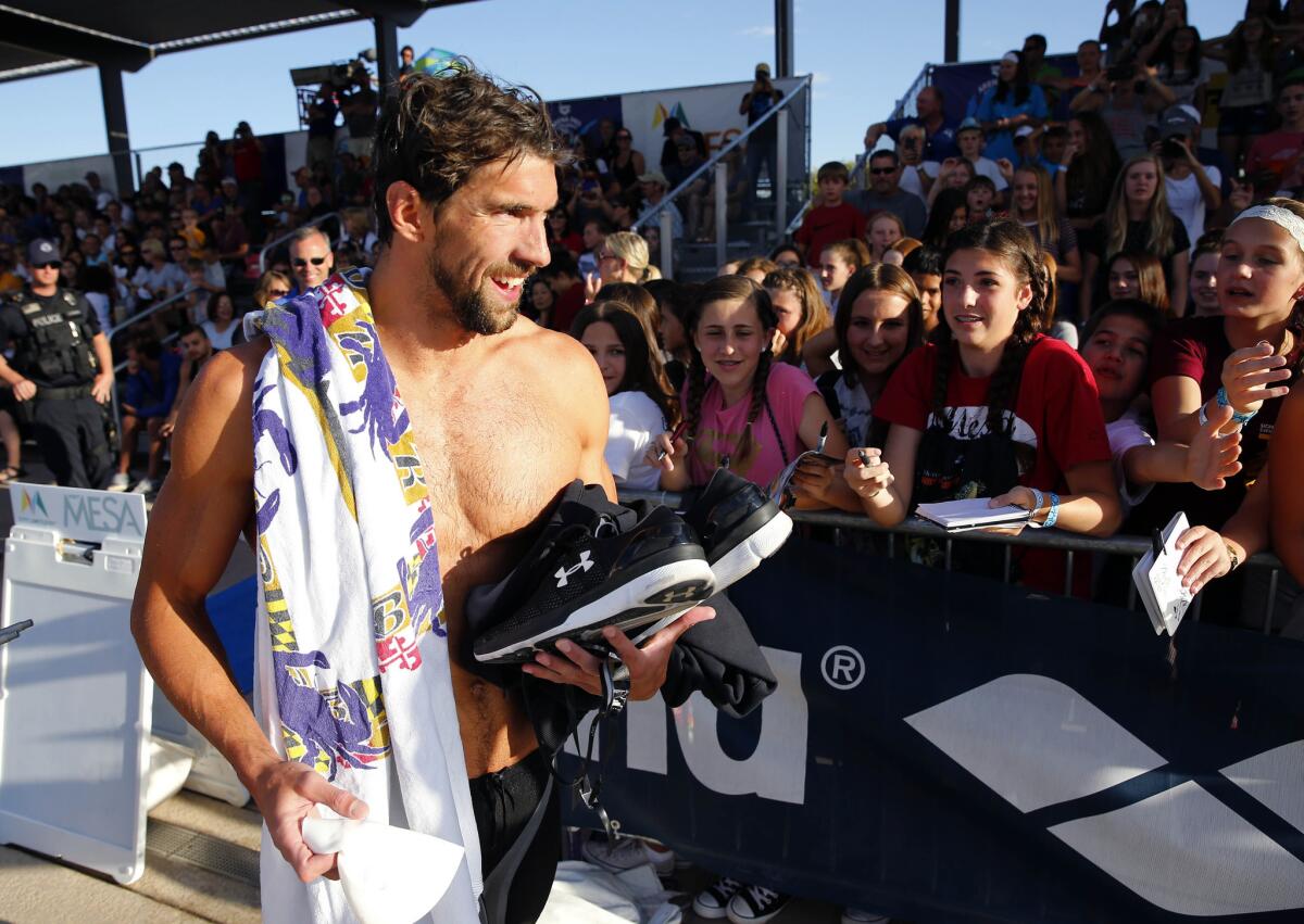 Michael Phelps walks past fans after competing in the 200-meter individual medley during the Arena Pro Swim Series swim meet April 16 in Mesa, Ariz.