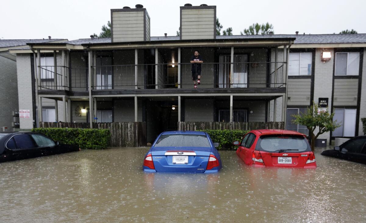 A resident looks out from the second floor as floodwaters surround his apartment complex in Houston on Monday.