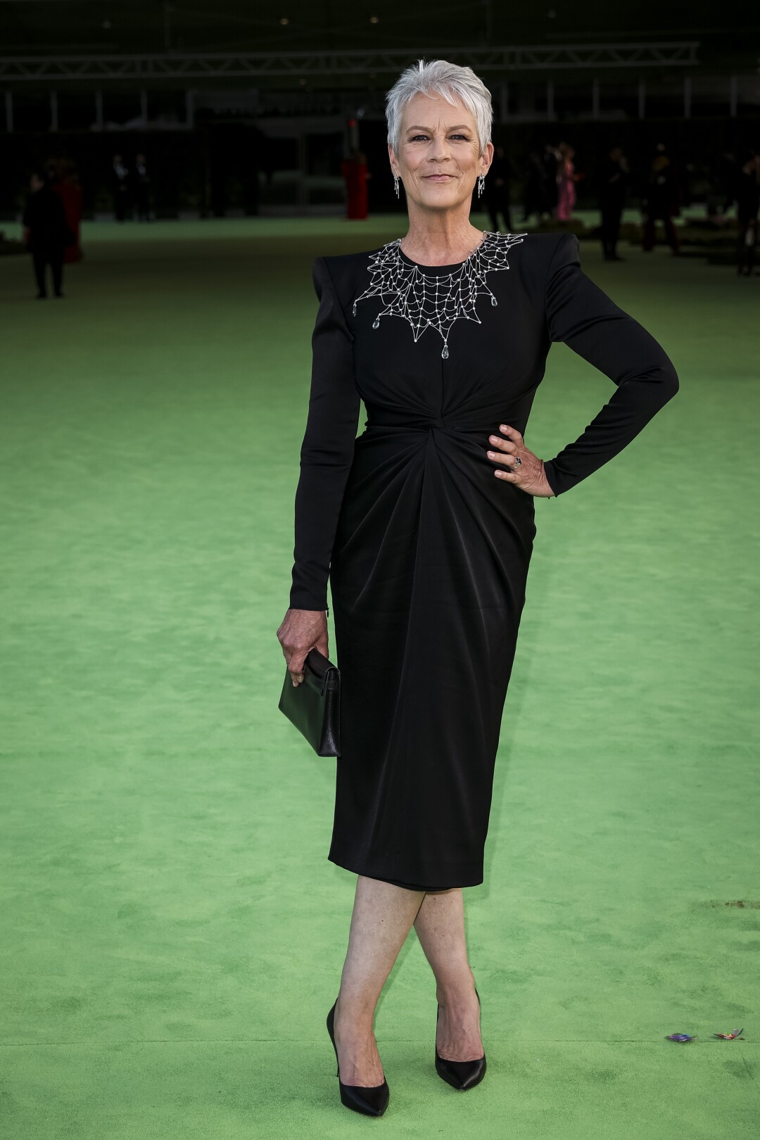 A woman in a black dress posing on a green carpet