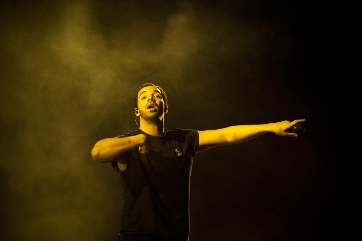 Drake, in a black T-shirt, holds his mic out to the audience at Coachella.