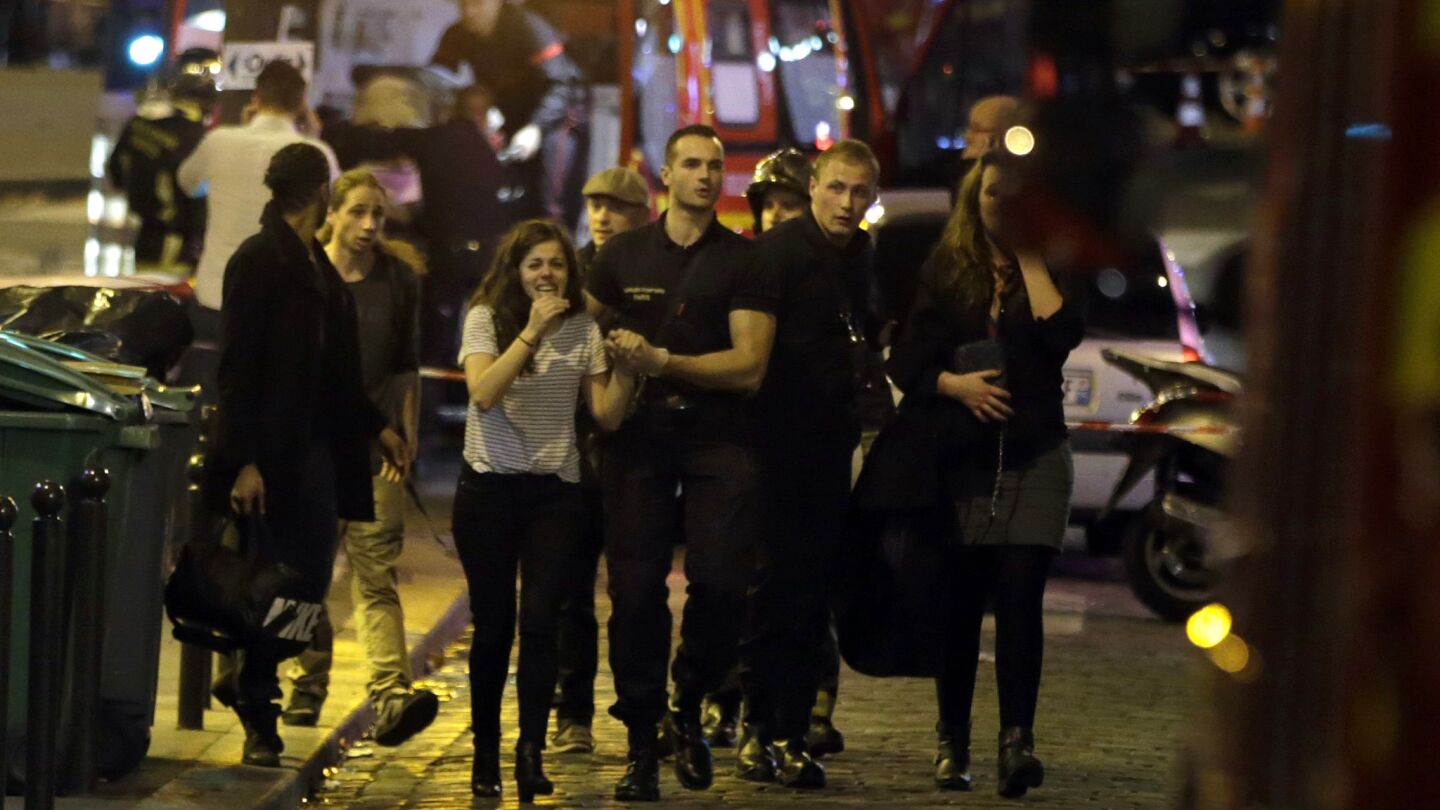 Rescuers evacuate people following an attack in Paris, where there were also reports of an ongoing hostage crisis at a concert venue.
