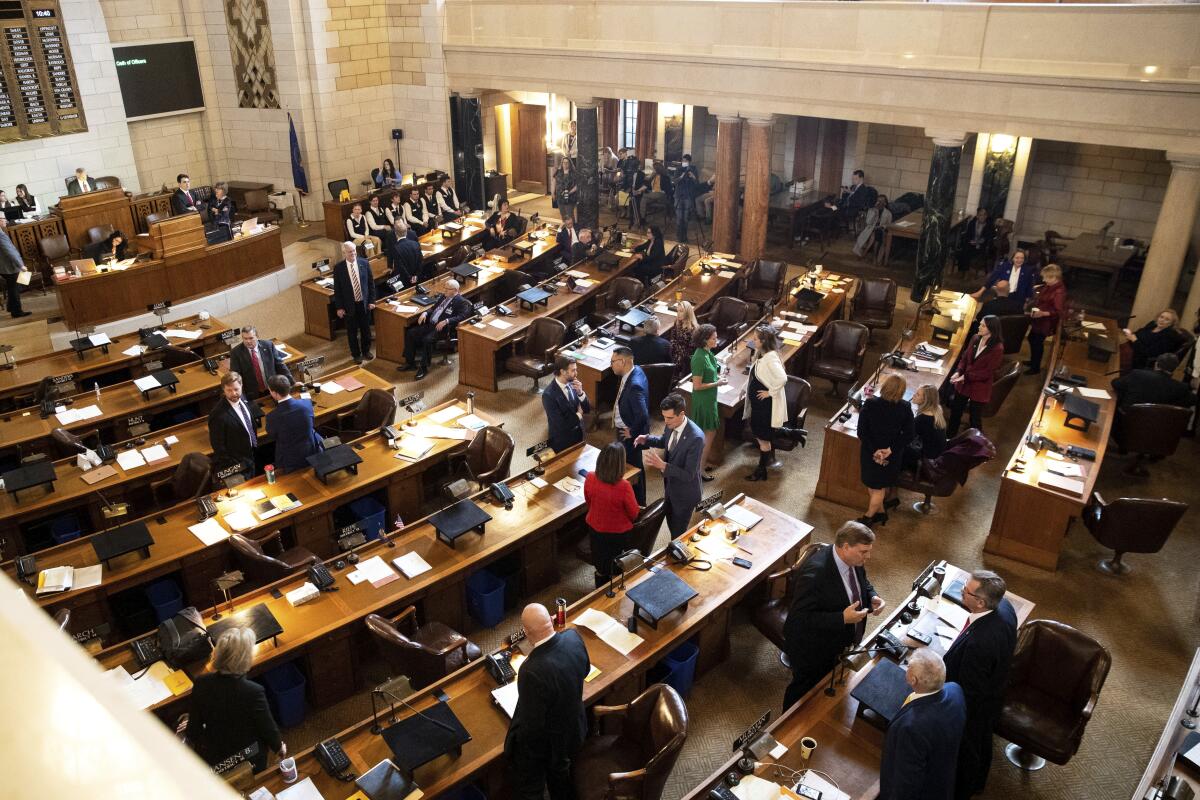 The Nebraska Legislature convenes in a room with long wooden tables.