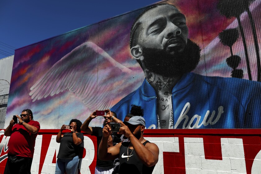 Visitors take pictures near the site of rapper and activist Nipsey Hussle’s March 31, 2019 slaying.