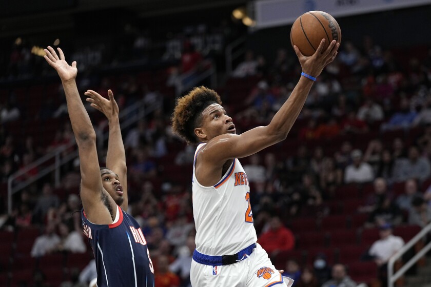 New York Knicks' Miles McBride, right, goes up for a shot as Houston Rockets' Josh Christopher defends during the first half of an NBA basketball game Thursday, Dec. 16, 2021, in Houston. (AP Photo/David J. Phillip)