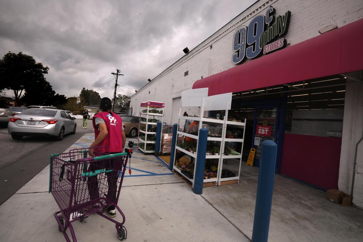 A worker collects a shopping cart outside a 99 Cents Only.