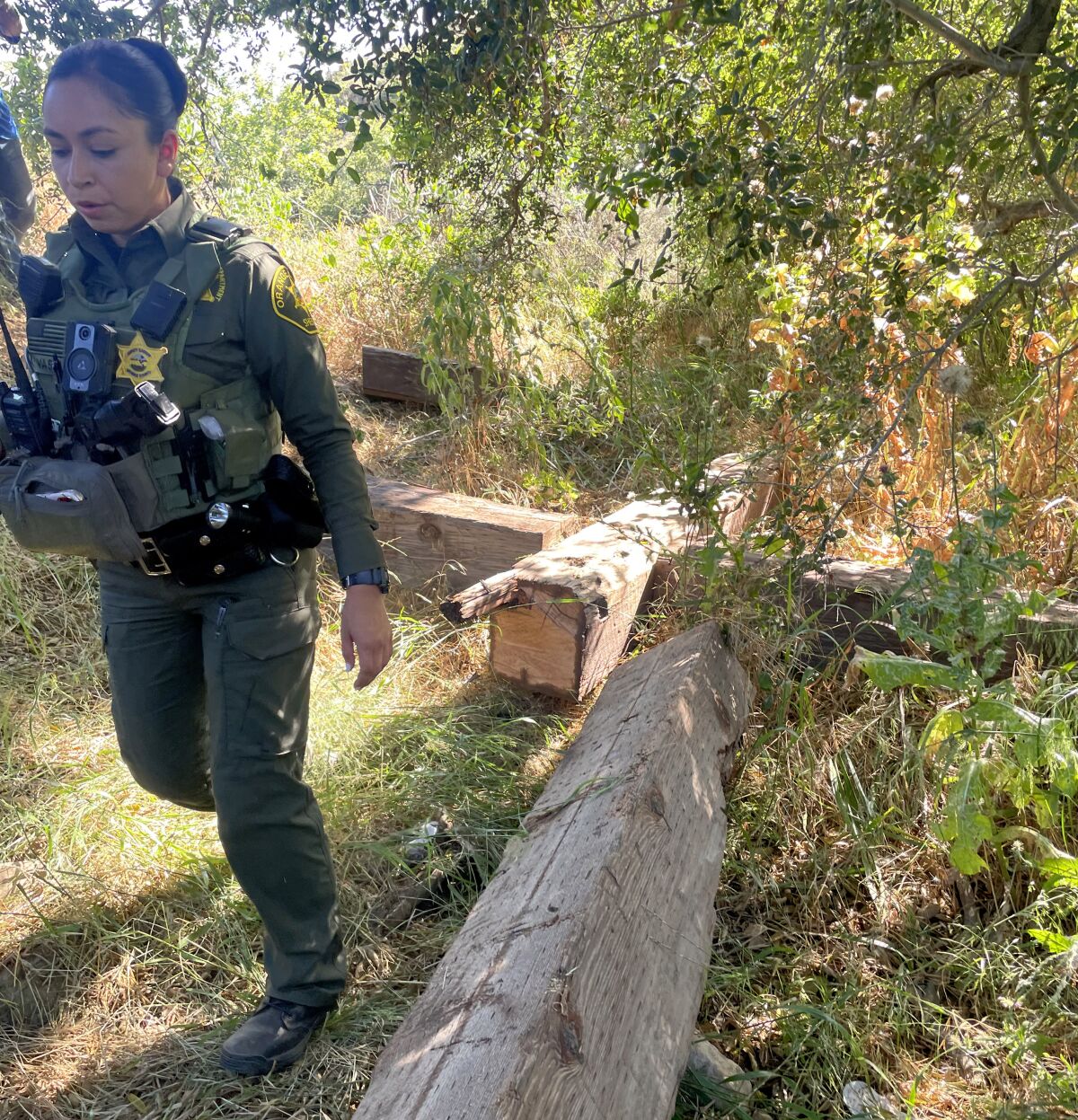 An Orange County sheriff's deputy walks by the sawed-down cross 