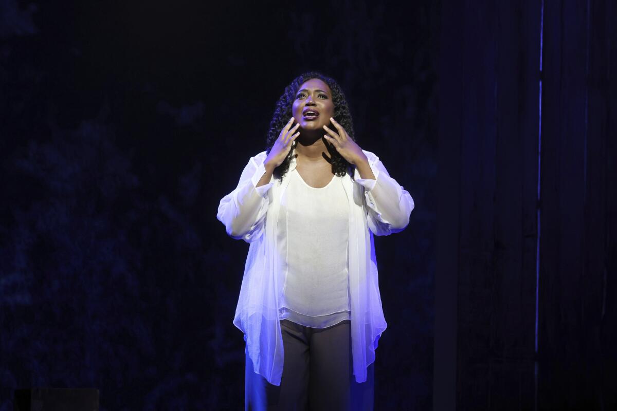 A woman in a white outfit singing on a stage.