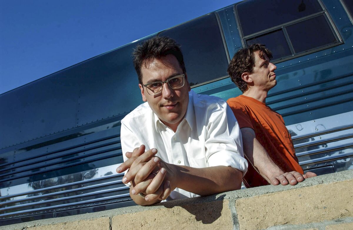 FILE - John Flansburgh, left, and John Linnell, members of the musical group They Might Be Giants, pose in front of their tour bus outside the John Anson Ford Theater in Los Angeles July 26, 2002. Flansburgh is recovering after being seriously injured in a car crash on Thursday, June 9, 2022 in New York City. (AP Photo/Ann Johansson, File)