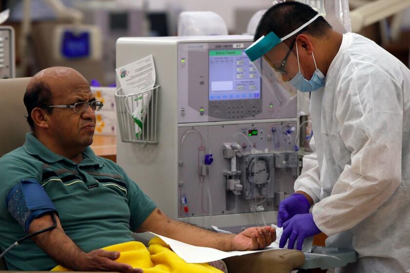 INGLEWOOD, CA. AUGUST 28, 2014 --- Giraldo Garcia, 54, left, waits for dialysis to start as patient care technician Leodegario Ventura, 33, prepares him for the process at DaVita Dialysis Center on August 28, 2014 in Inglewood. (Irfan Khan / Los Angeles Times)