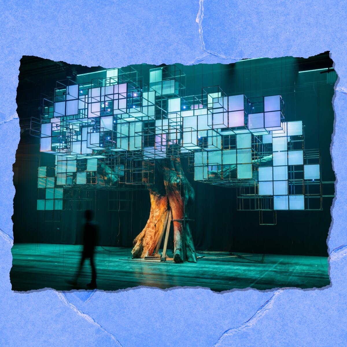 A structure on a stage looks like a tree trunk holding up a metal structure of cubes.