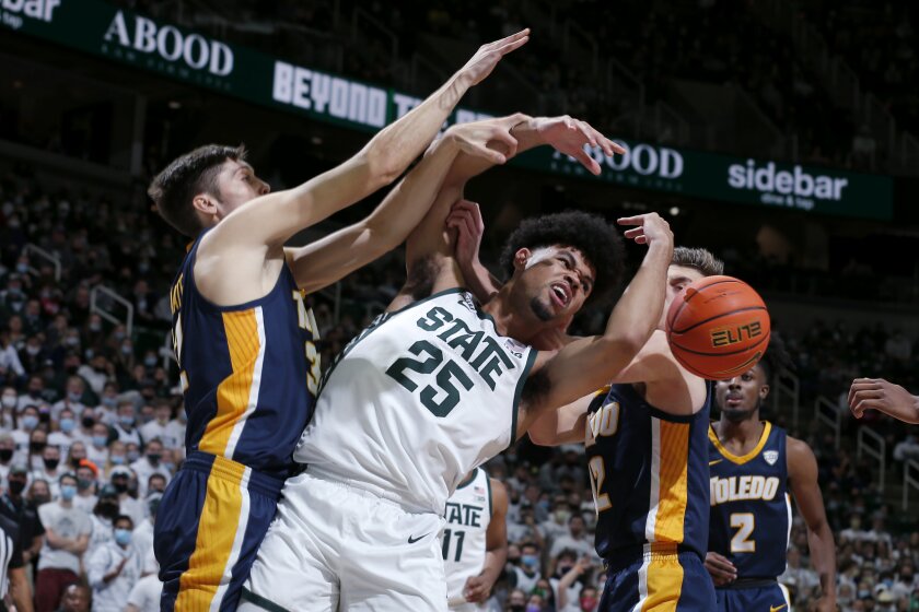 Michigan State's Malik Hall, center, and Toledo's JT Shumate, left, and Kooper Jacobi fight for a rebound during the first half of an NCAA college basketball game, Saturday, Dec. 4, 2021, in East Lansing, Mich. (AP Photo/Al Goldis)