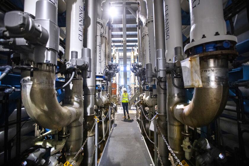 Carlsbad, CA - March 30: Michelle Peters, technical and compliance manager for Poseidon Water, walks through the reverse osmosis building, which contains more than 2,000 pressure vessels that each contain a series of reverse osmosis membranes at the Claude "Bud" Lewis Carlsbad Desalination Plant, which opened on December 14, 2015 in Carlsbad. The byproduct of reverse osmosis-called brine-contains roughly twice as much salt as seawater. Before it's released into the ocean, bride from the plant is diluted with seawater to reduce its salinity and ensure minimal impacts to the ocean. According to Poseidon, the Carlsbad Desalination Plant uses 100 million gallons of seawater on an average day from the Pacific Ocean that enters through an intake on the shores of Agua Hedionda Lagoon. Seawater is drawn into the pump stations dn transported to the plant via the 72-inch seawater feed pipe to begin the desalination process. Photo taken in Carlsbad Desalination Plant in Carlsbad, CA on Wednesday, March 30, 2022. (Allen J. Schaben / Los Angeles Times)