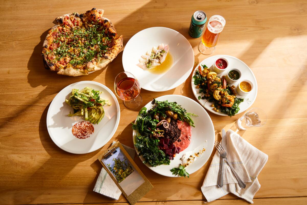 An overhead photo of a spread of forthcoming dishes from Lemon Grove, including pizza, seafood crudo and seasonal vegetables.