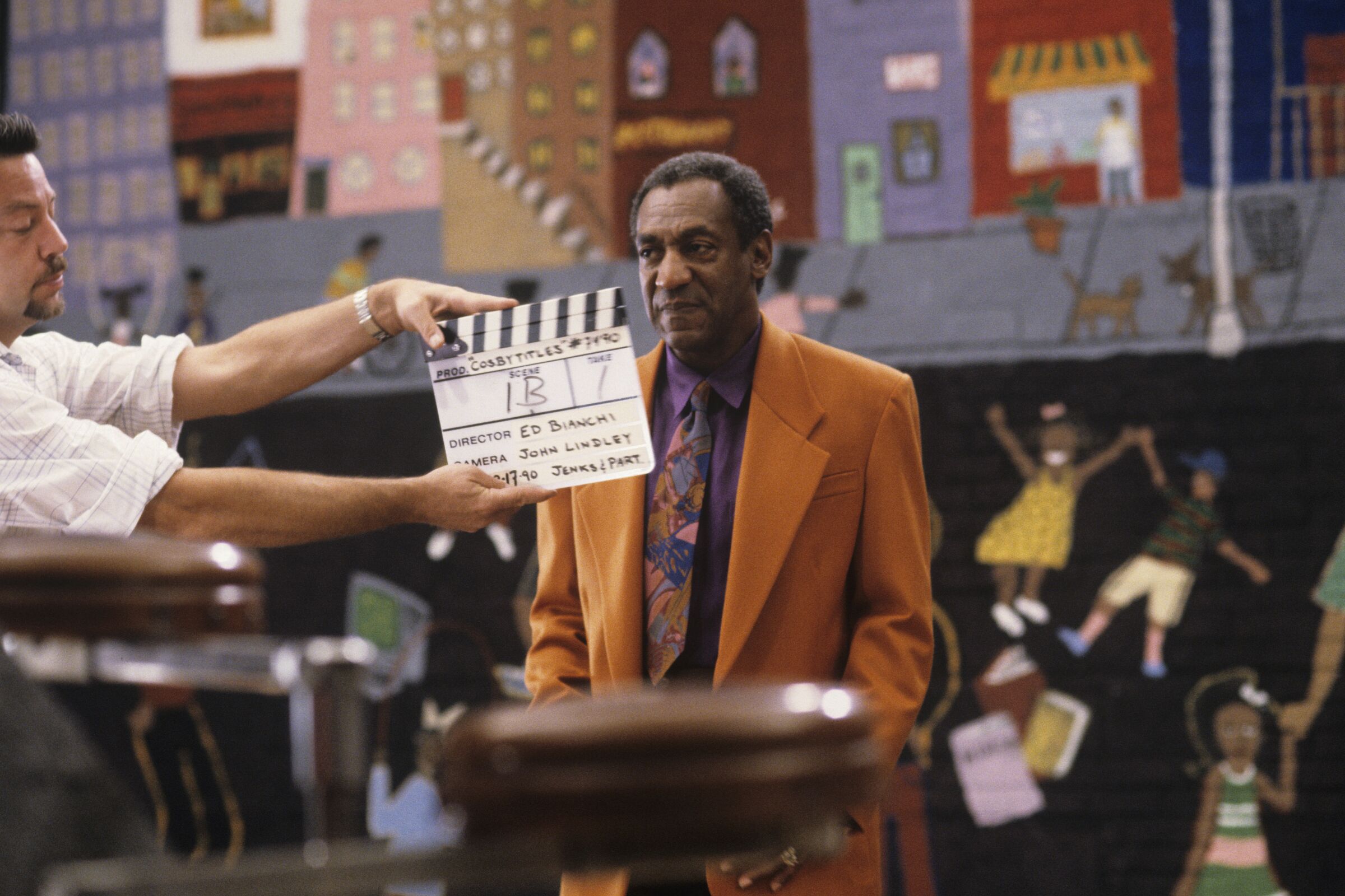Bill Cosby in an orange suit on a TV set