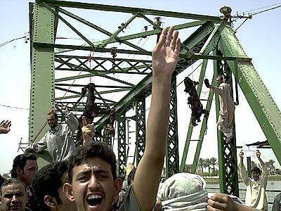 A crowd gathers as charred bodies hang from a bridge over the Euphrates River in Fallujah, west of Baghdad. Enraged Iraqis in this hotbed of anti-Americanism killed four foreigners Wednesday, including at least one U.S. national, took the charred bodies from a burning SUV, dragged them through the streets, and hung them from the bridge.