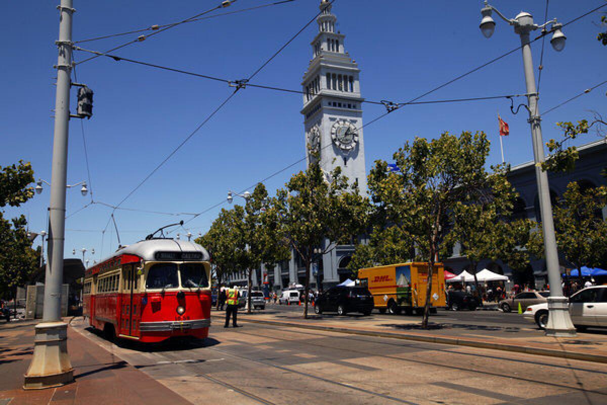 A brightly colored trolley cruises down the Embarcadero past the Ferry Building in San Francisco.
