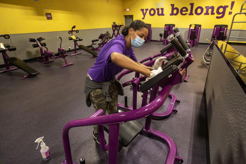 INGLEWOOD, CA - MARCH 15: Lenterra Daniels, an employee at Planet Fitness on Imperial Highway in Inglewood, disinfects an abdominal resistance machine while helping to prepare the fitness center for their re-opening tomorrow morning at 5am after being closed since July of 2020. The new guidelines allow for a maximum of 10 percent of capacity. (Mel Melcon / Los Angeles Times)