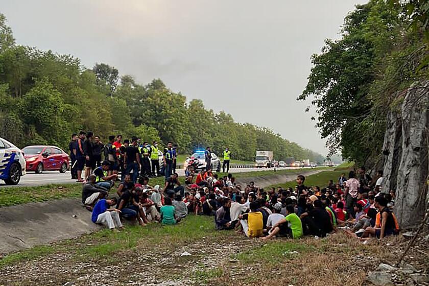 In this photo released by the Malaysia Royal Police, police detain Rohingya refugees who had escaped from the Sungai Bakap Temporary Immigration Depot, Penang, Malaysia, Wednesday, April 20, 2022. More than 500 Rohingya refugees escaped from detention in Malaysia following a protest and most have been rearrested. (Malaysia Royal Police via AP)