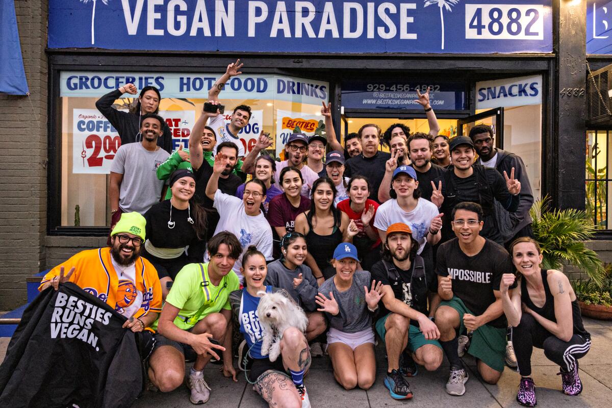 A group portrait of people in athletic wear in front of Besties Vegan Paradise.