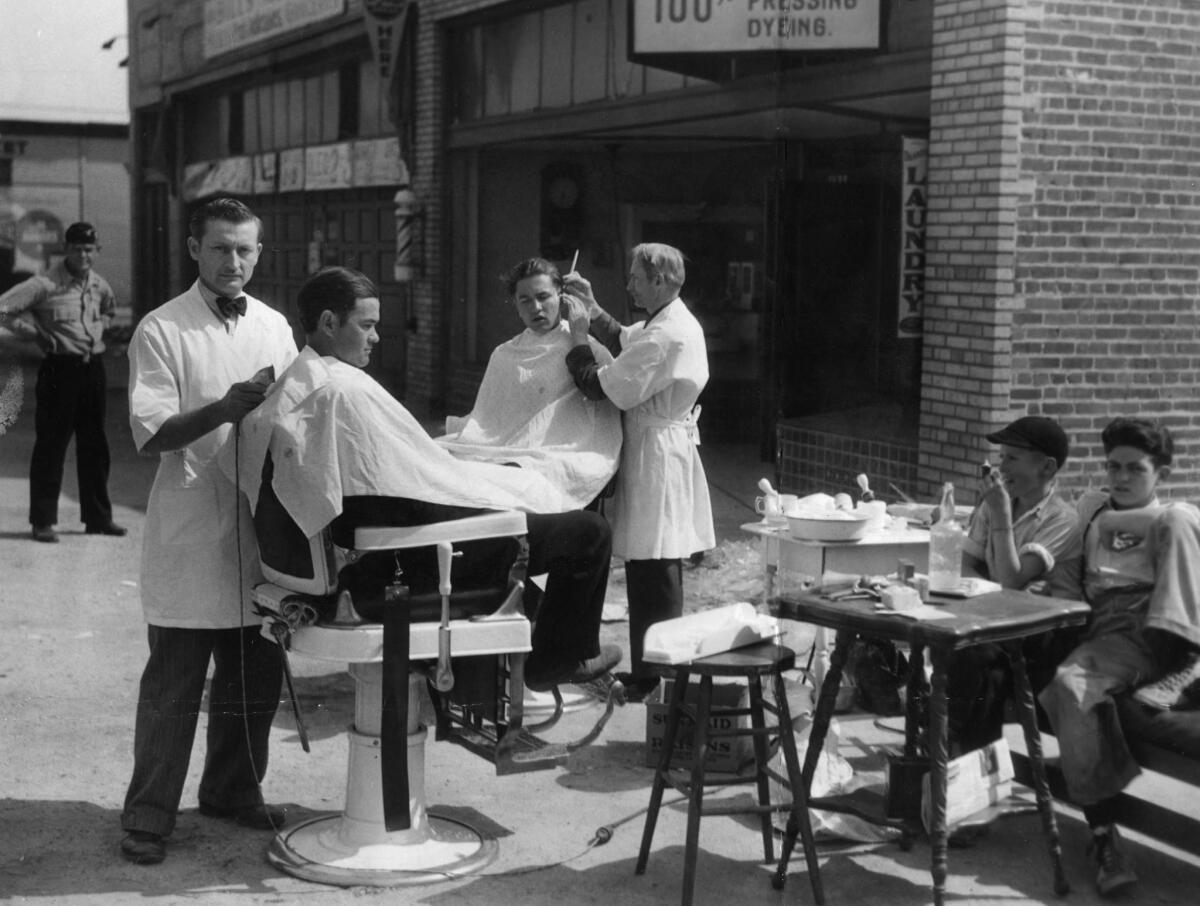 March 11, 1933: The Wess Barber Shop in Florence section of Los Angeles was destroyed by the March 10, 1933, Long Beach earthquake. Owner Wesley Boyts, left, and barber Ernest Lentz cut hair on the sidwalk.